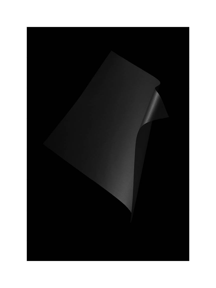 Abstrakt minimalistiskt fotografi med mörka, skulpturala former mot svart bakgrund.