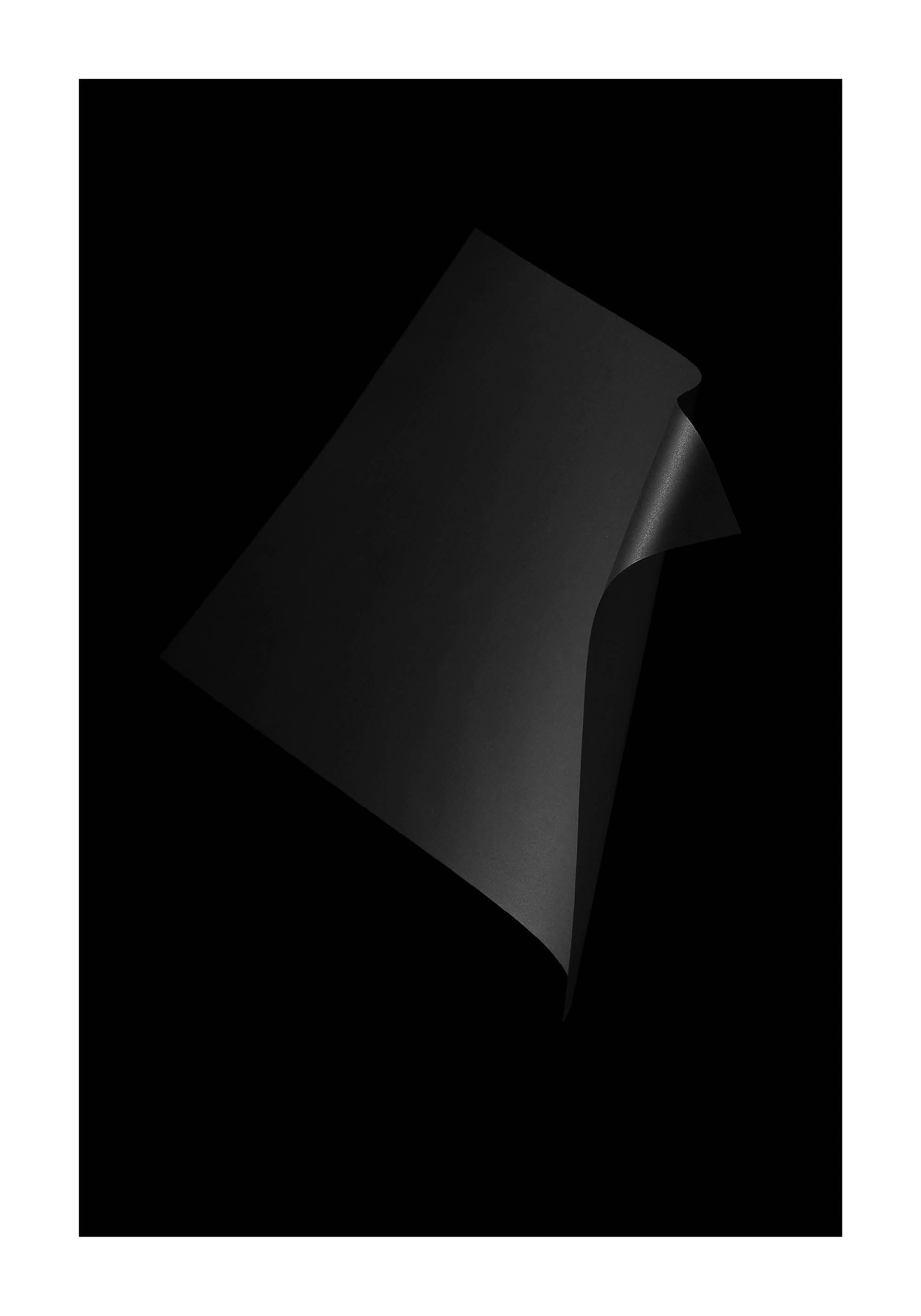 Abstrakt minimalistiskt fotografi med mörka, skulpturala former mot svart bakgrund.