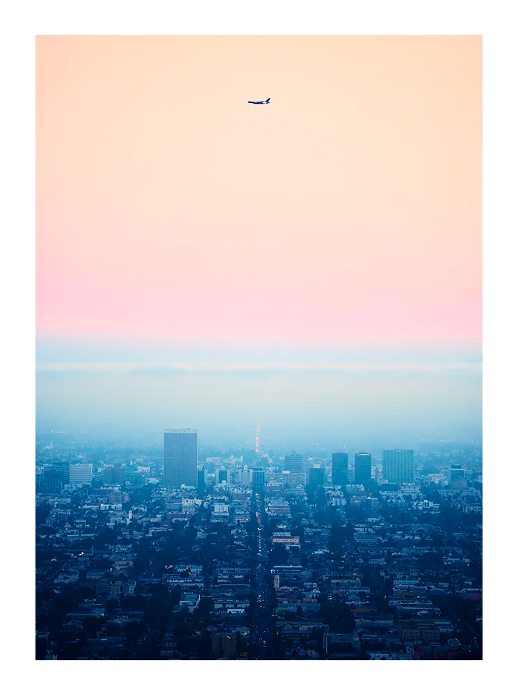 Minimalist fine art photograph of Los Angeles at dusk with an airplane silhouette against a pastel sky. Printed in Sweden, exclusive at Monday Gallery.