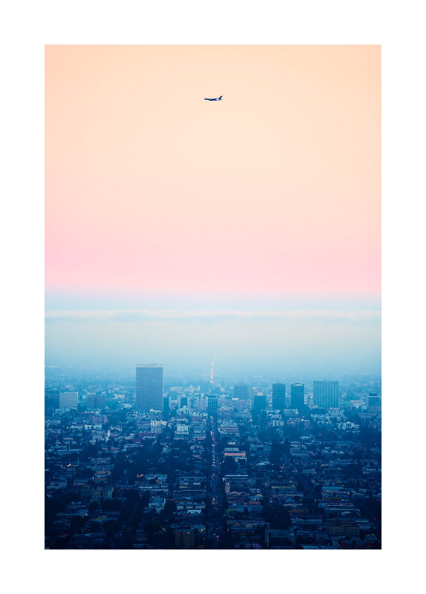 Minimalist fine art photograph of Los Angeles at dusk with an airplane silhouette against a pastel sky. Printed in Sweden, exclusive at Monday Gallery.