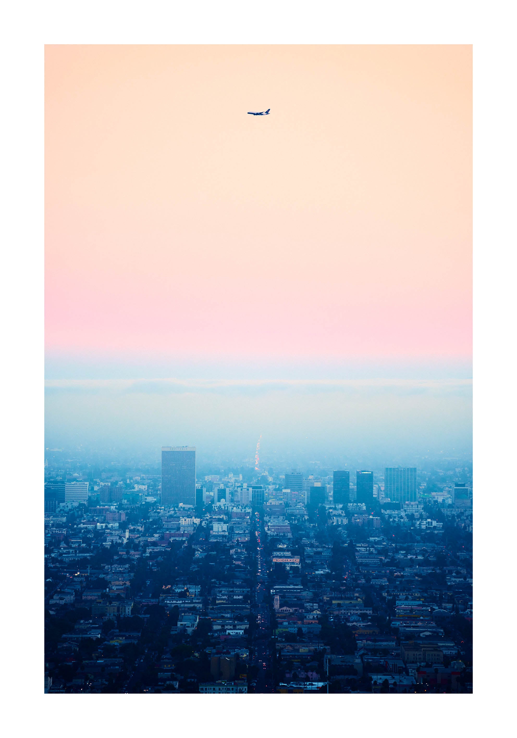 Minimalist fine art photograph of Los Angeles at dusk with an airplane silhouette against a pastel sky. Printed in Sweden, exclusive at Monday Gallery.