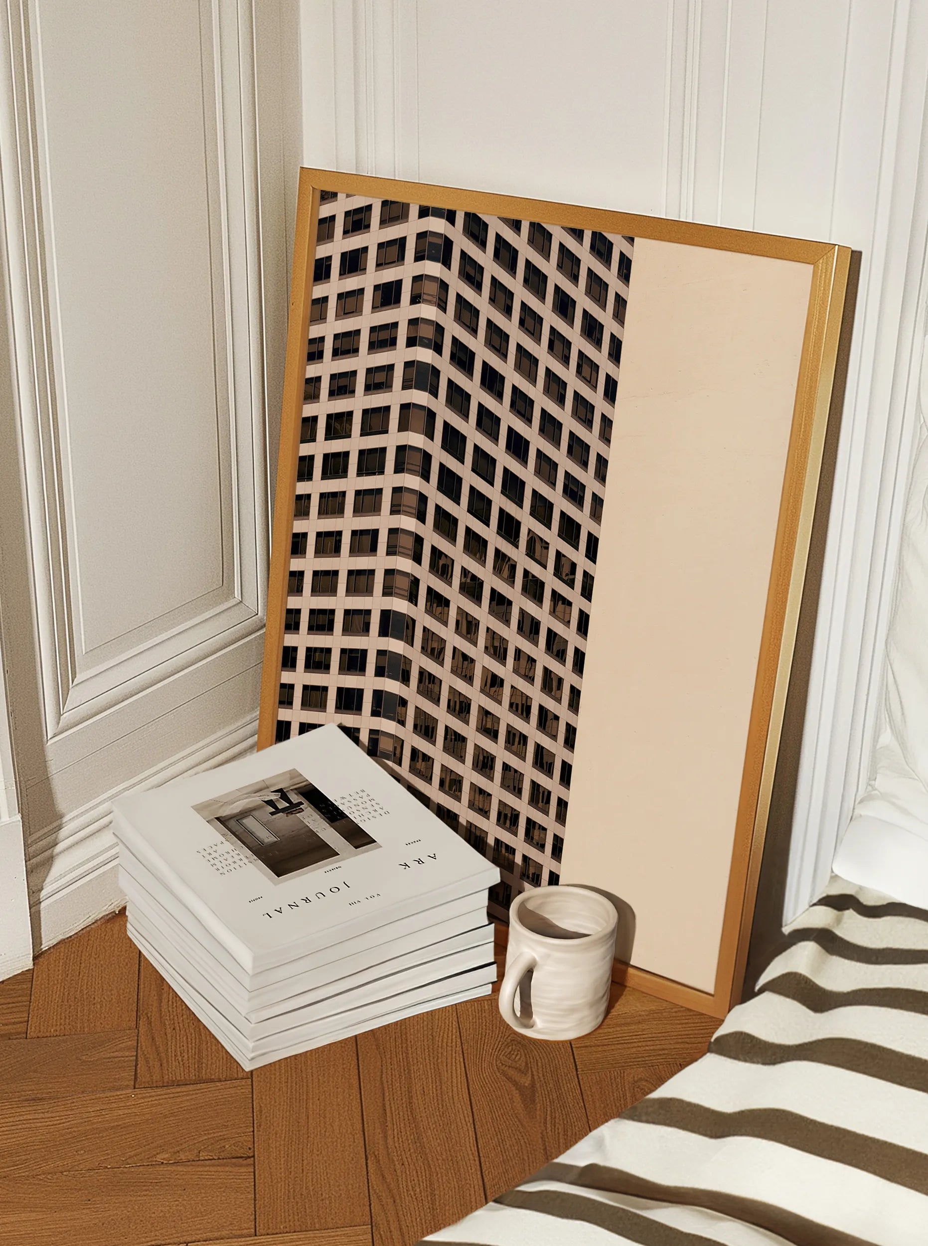 Framed minimalist fine art print with architectural grid design leaning against a wall beside books and a ceramic mug on a wooden floor.