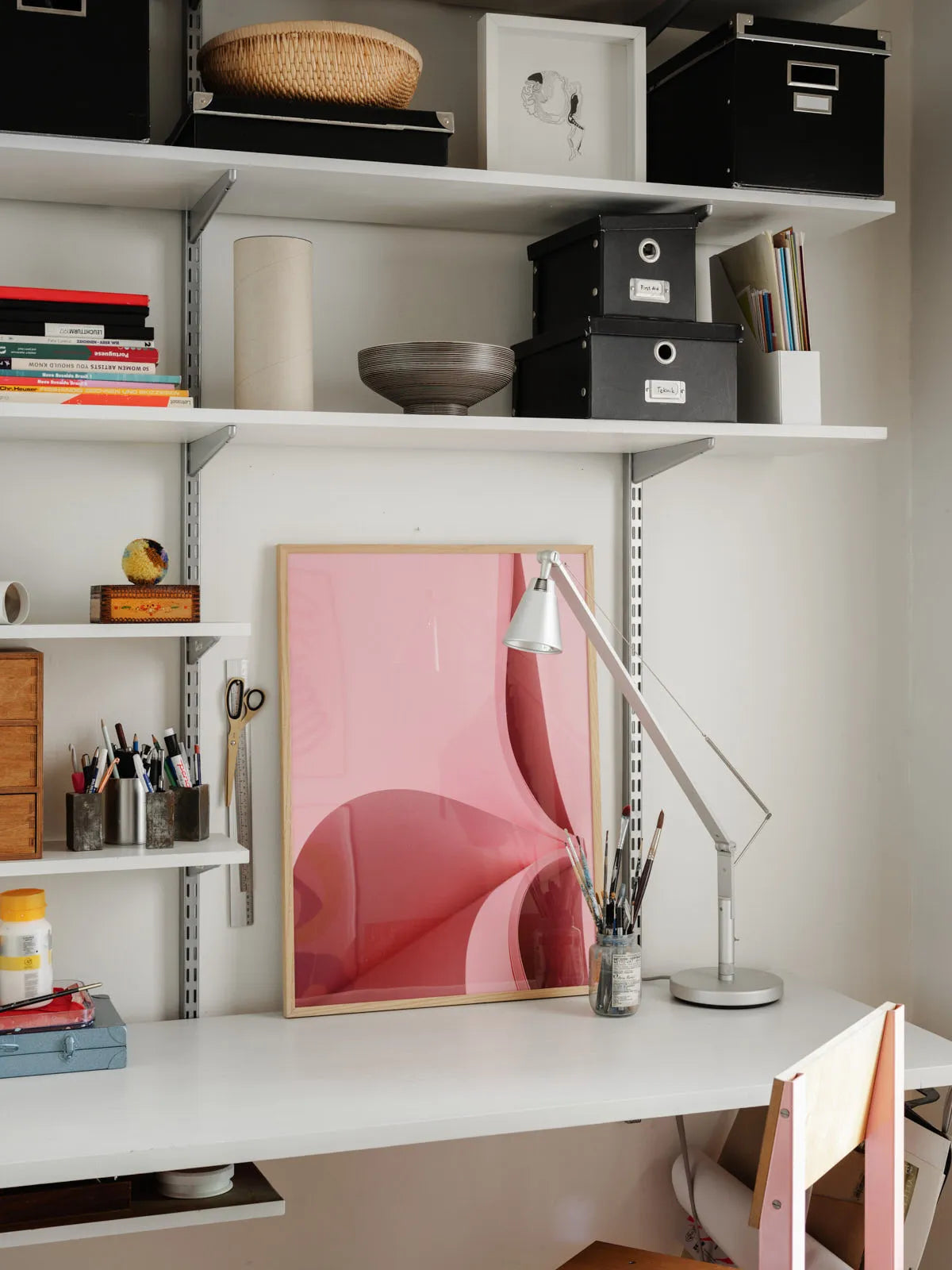 Minimalist workspace with framed Pink Perspective No.1 fine art print in soft pink tones, styled on a white desk with art supplies. Scandinavian interior. Printed in Sweden, exclusive at Monday Gallery.