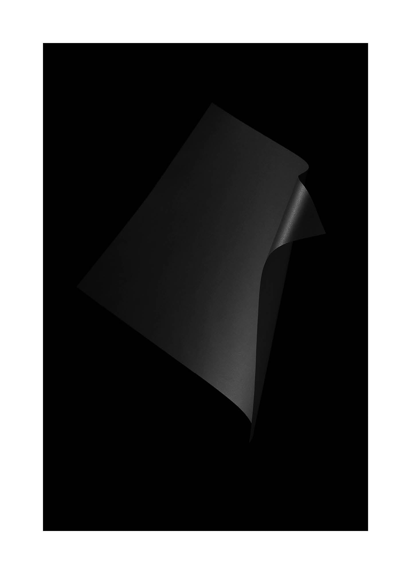 Abstrakt minimalistiskt fotografi med mörka, skulpturala former mot svart bakgrund.