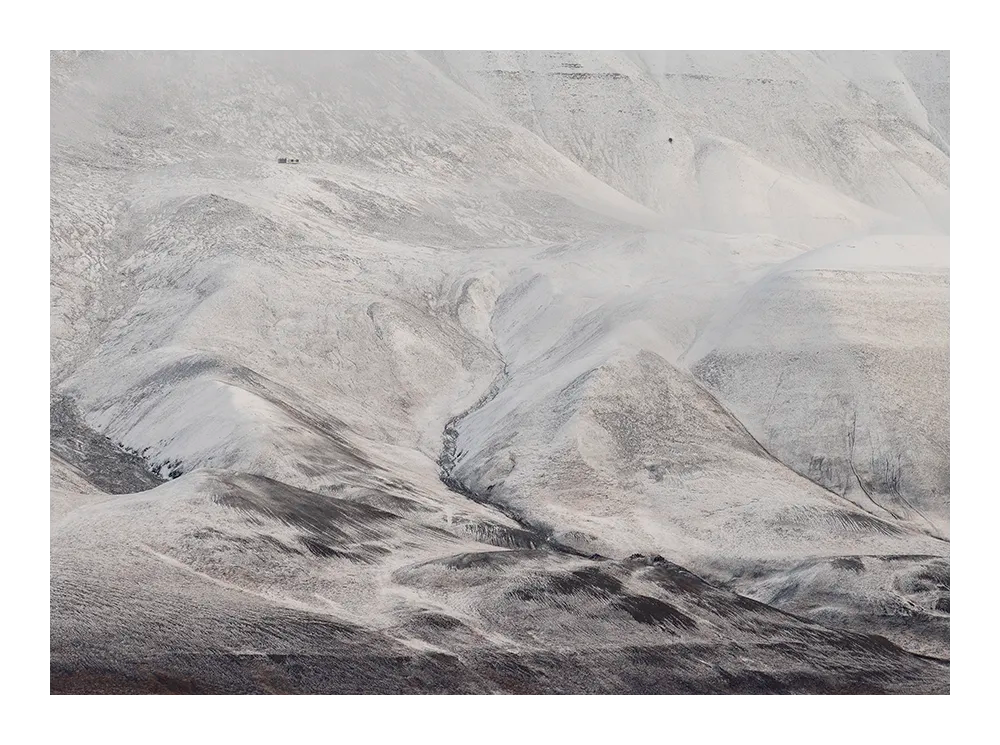 Minimalist landscape photograph of Svalbard’s snow-covered mountains in soft, muted tones.