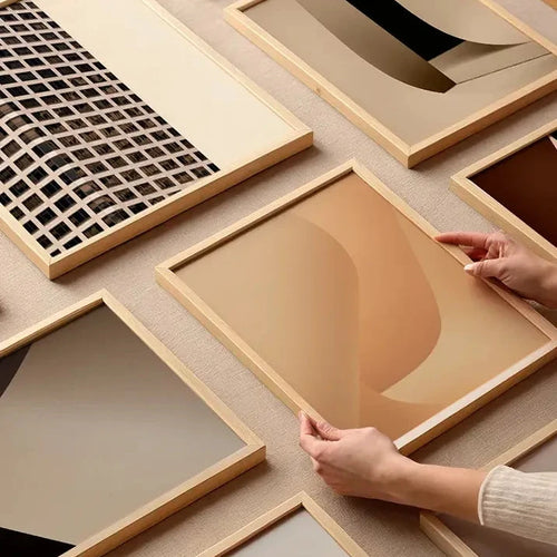 Collection of framed fine art prints from Monday Gallery, including “Beige Simplicity No.1”, arranged on a neutral surface with hands interacting.