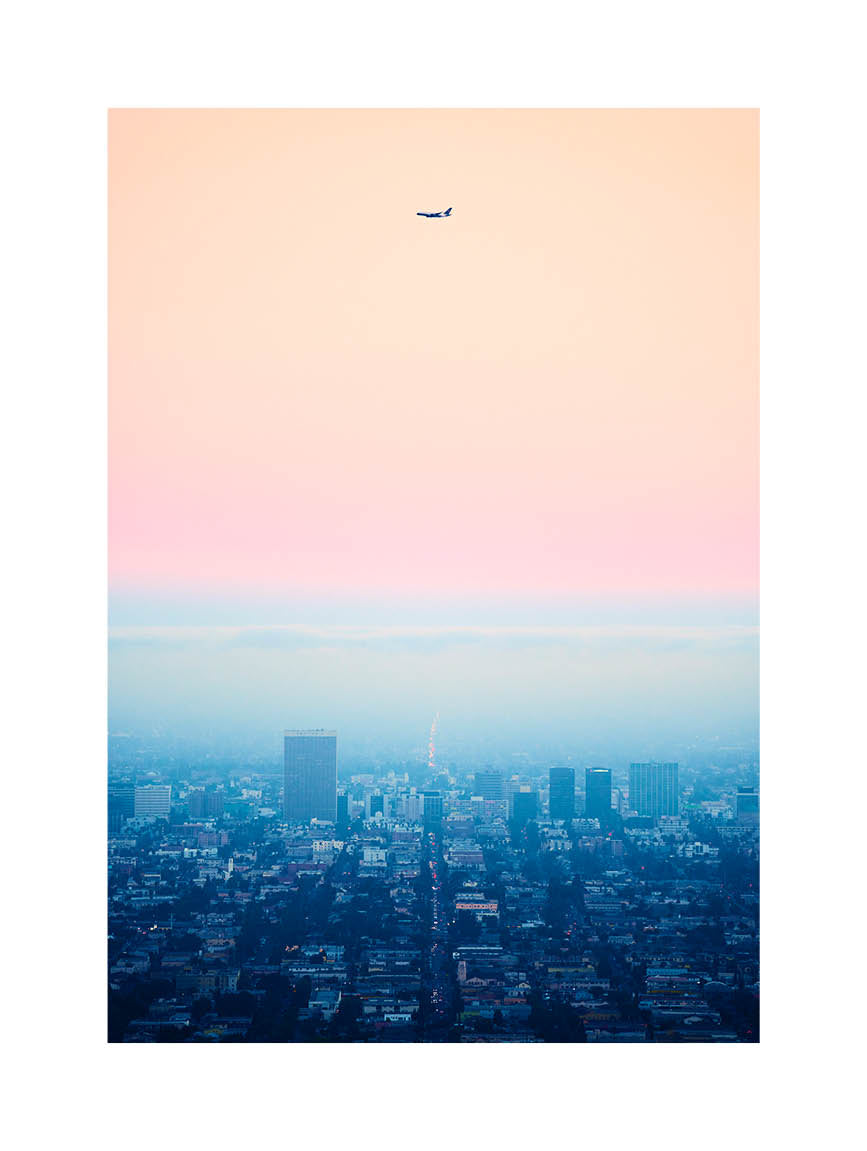 Minimalist fine art photograph of Los Angeles at dusk with an airplane silhouette against a pastel sky. Printed in Sweden, exclusive at Monday Gallery.