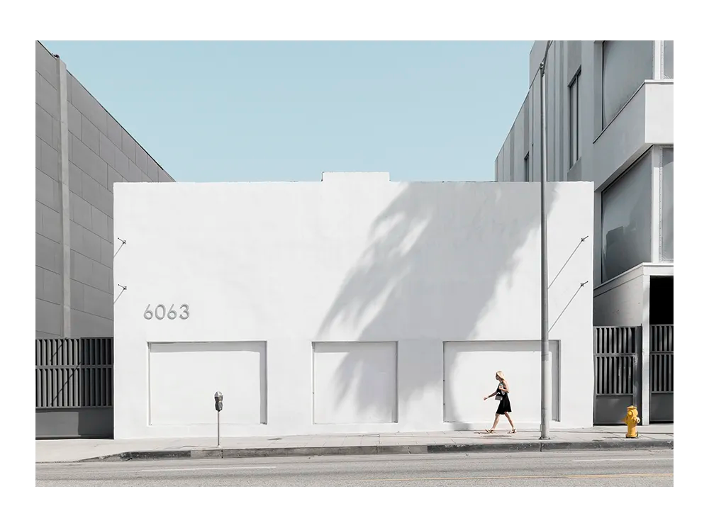 minimalist urban photograph of a white modern building with a person walking by in soft daylight