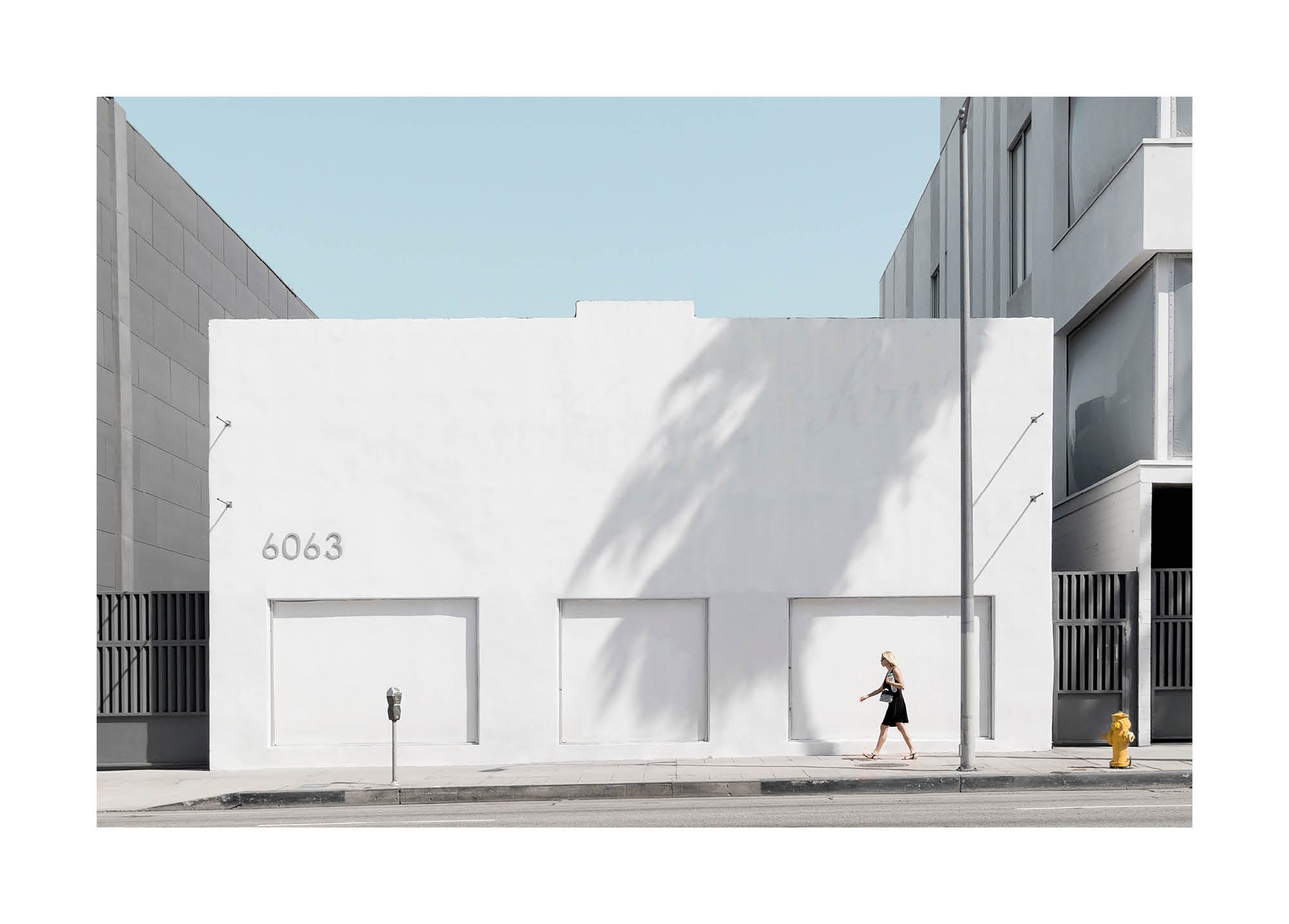minimalist urban photograph of a white modern building with a person walking by in soft daylight